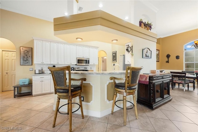 18510 Ellen Ave, Port Charlotte, FL 33948 - kitchen with white cabinets, stainless steel microwave, arched walkways, and a kitchen bar