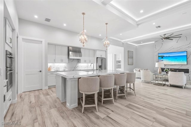 9974 Winterview Dr, Naples, FL 34109 - kitchen with appliances with stainless steel finishes, a chandelier, open floor plan, a center island with sink, and light wood-type flooring