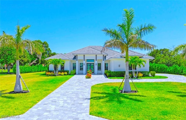 9974 Winterview Dr, Naples, FL 34109 - view of front facade featuring a front yard, stucco siding, decorative driveway, french doors, and a tiled roof