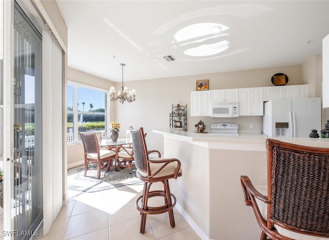 4660 Winged Foot Ct Unit 102, Naples, FL 34112 - kitchen with white appliances, a kitchen bar, visible vents, white cabinets, and a chandelier