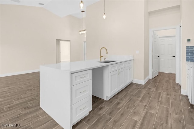 4911 Bywood St, Lehigh Acres, FL 33971 - kitchen featuring a sink, wood finish floors, a peninsula, white cabinetry, and vaulted ceiling