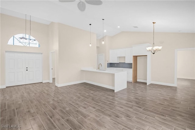 4911 Bywood St, Lehigh Acres, FL 33971 - kitchen featuring high vaulted ceiling, a chandelier, a sink, a peninsula, and white cabinets