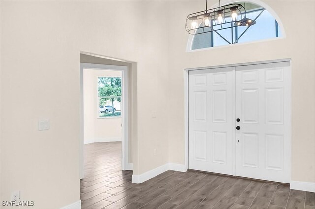 4911 Bywood St, Lehigh Acres, FL 33971 - foyer featuring a chandelier, wood finished floors, baseboards, and a high ceiling