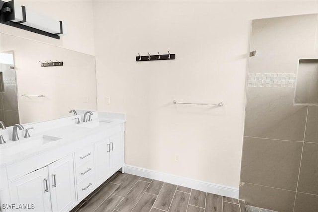 4911 Bywood St, Lehigh Acres, FL 33971 - bathroom with double vanity, baseboards, wood finished floors, and a tile shower