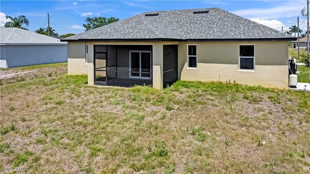 4911 Bywood St, Lehigh Acres, FL 33971 - back of house with a shingled roof, a sunroom, stucco siding, and a lawn