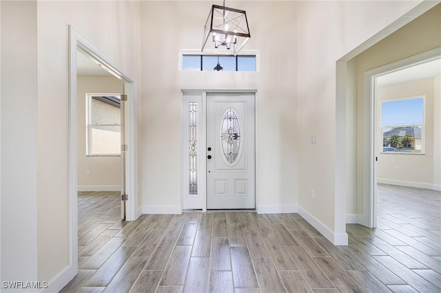 4909 Berryman St, Lehigh Acres, FL 33971 - entryway featuring wood finish floors, a high ceiling, baseboards, and an inviting chandelier