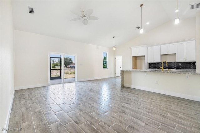 4909 Berryman St, Lehigh Acres, FL 33971 - kitchen featuring decorative backsplash, open floor plan, ceiling fan, wood finish floors, and visible vents