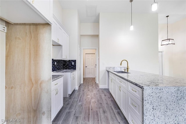 4909 Berryman St, Lehigh Acres, FL 33971 - kitchen with light stone counters, a sink, a peninsula, white cabinetry, and visible vents
