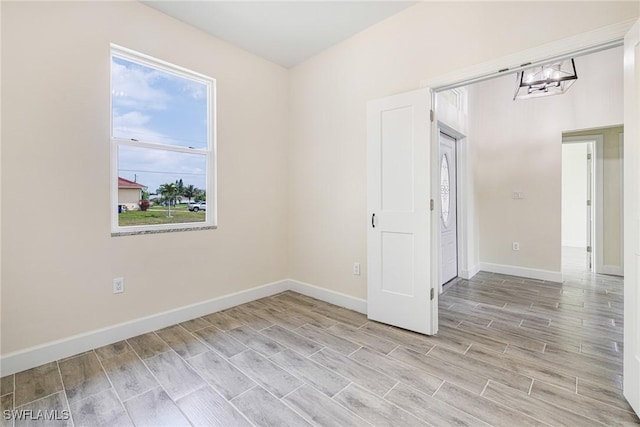4909 Berryman St, Lehigh Acres, FL 33971 - unfurnished room featuring wood tiled floor, baseboards, and an inviting chandelier