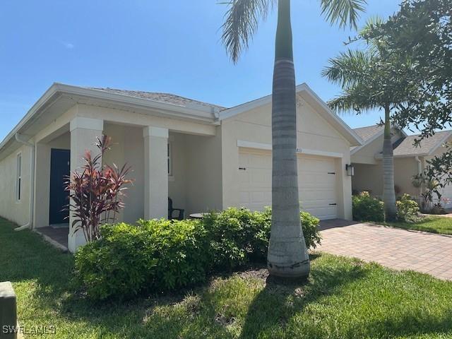 8813 Swell Brooks Ct, North Fort Myers, FL 33917 - view of front of house with stucco siding, a garage, and decorative driveway