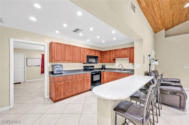 kitchen featuring a sink, visible vents, black appliances, and a kitchen bar