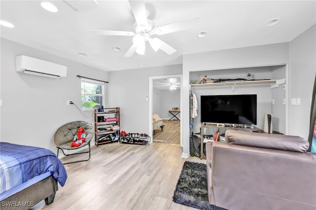 bedroom featuring a ceiling fan, recessed lighting, light wood-style floors, and a wall unit AC