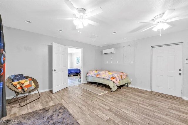 bedroom with light wood-style floors, a wall mounted air conditioner, baseboards, and a ceiling fan