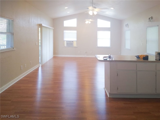 interior space with cooling unit, a ceiling fan, wood finished floors, lofted ceiling, and baseboards