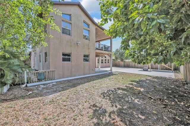 rear view of property featuring a patio, a fenced backyard, stucco siding, and a balcony