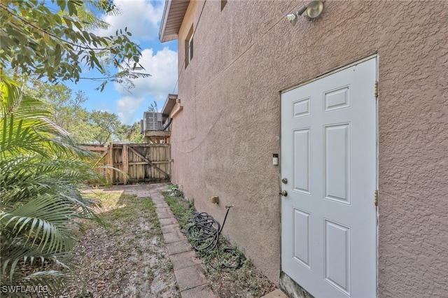 view of exterior entry featuring fence and stucco siding
