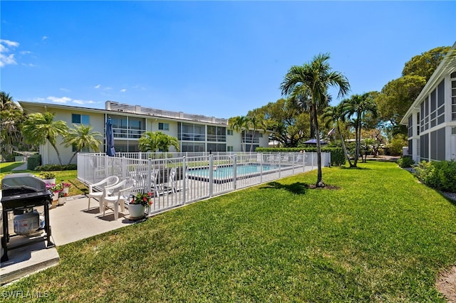 community pool featuring a patio area, area for grilling, fence, and a lawn