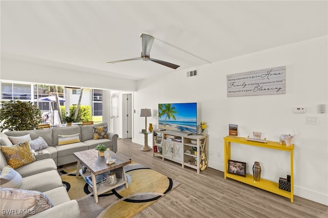 living room featuring a ceiling fan, baseboards, visible vents, and wood finished floors