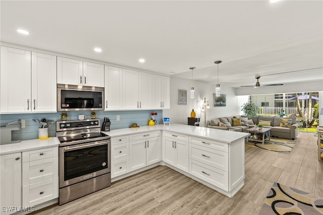 kitchen featuring a peninsula, stainless steel appliances, open floor plan, light countertops, and light wood-style floors