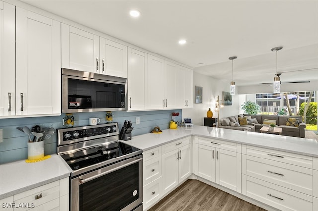 kitchen with light wood finished floors, open floor plan, light countertops, and appliances with stainless steel finishes