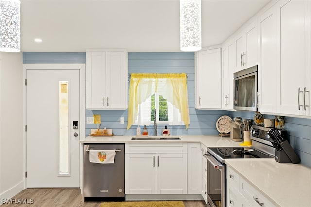 kitchen with white cabinetry, light countertops, stainless steel appliances, and a sink