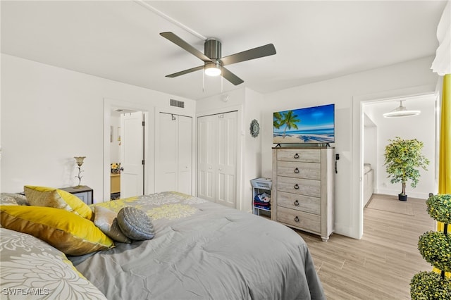 bedroom with a ceiling fan, baseboards, ensuite bathroom, visible vents, and light wood-style floors