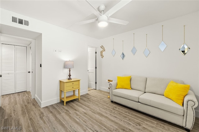 living room with visible vents, light wood-style flooring, baseboards, and ceiling fan