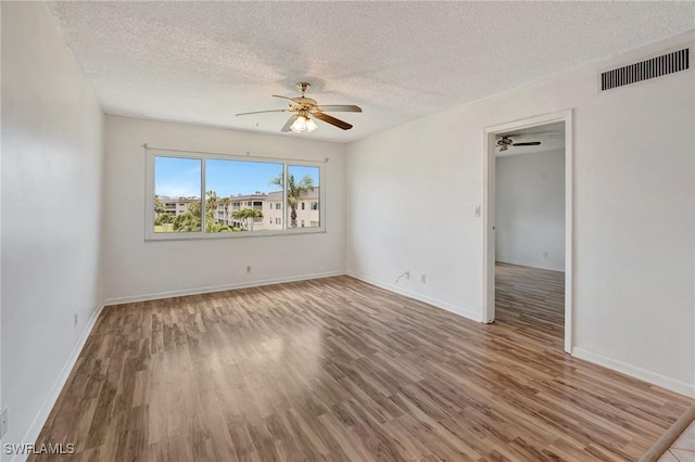 empty room featuring a textured ceiling, ceiling fan, and visible vents