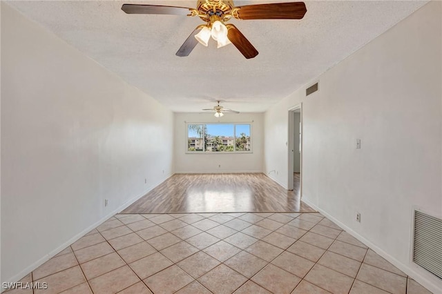 unfurnished room featuring light tile patterned floors, ceiling fan, a textured ceiling, and visible vents
