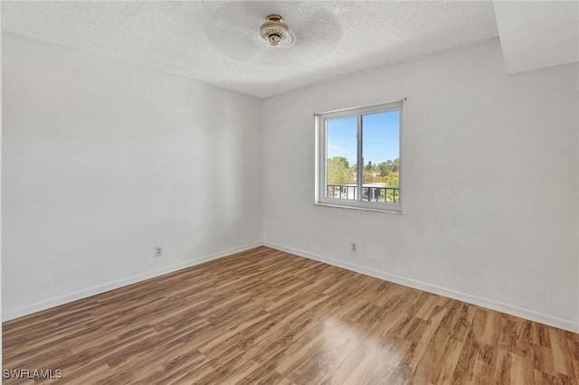 unfurnished room with baseboards, a textured ceiling, and wood finished floors
