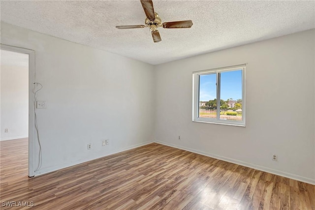 empty room featuring baseboards, a ceiling fan, a textured ceiling, and wood finished floors
