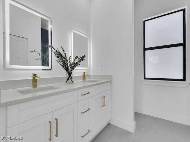 full bathroom featuring a sink, baseboards, and double vanity