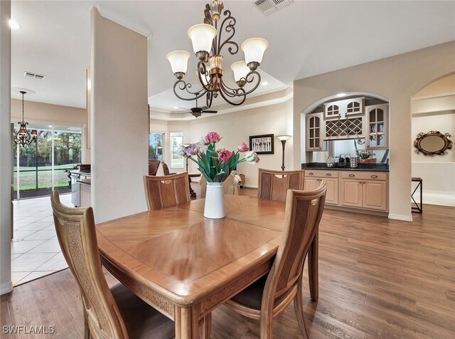 317 Harvard Ln, Naples, FL 34104 - dining area with a chandelier, wood finished floors, a raised ceiling, bar, and recessed lighting