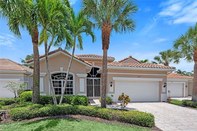 317 Harvard Ln, Naples, FL 34104 - mediterranean / spanish house featuring stucco siding, an attached garage, decorative driveway, and a tiled roof