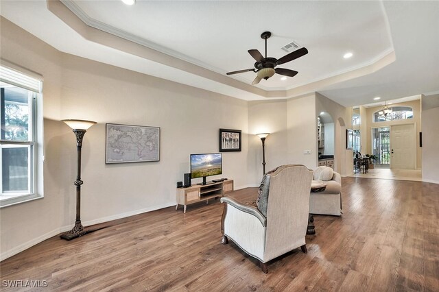 317 Harvard Ln, Naples, FL 34104 - living room featuring a tray ceiling, wood finished floors, ornamental molding, a ceiling fan, and arched walkways