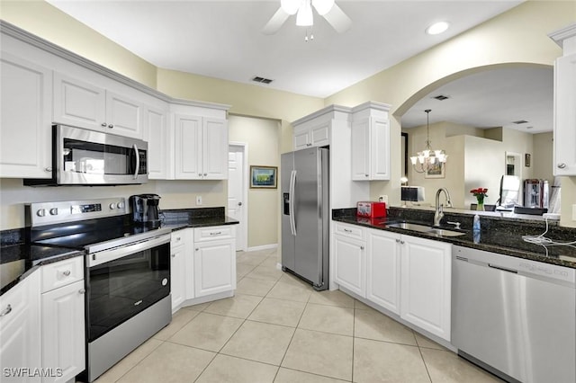 kitchen featuring stainless steel appliances, arched walkways, a sink, visible vents, and ceiling fan with notable chandelier
