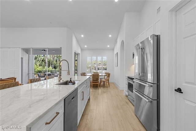 595 31st St NW, Naples, FL 34120 - kitchen with appliances with stainless steel finishes, a sink, white cabinets, light wood-style floors, and light stone counters