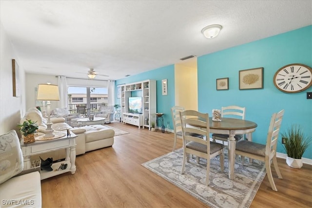 dining room featuring light wood-style floors, visible vents, baseboards, and a ceiling fan
