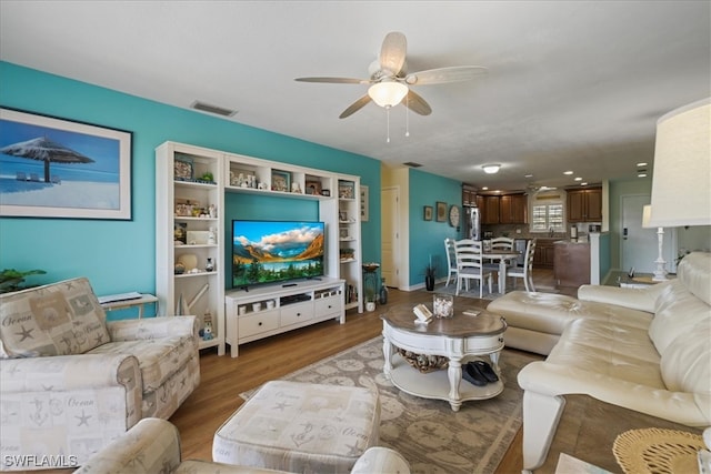 living area with visible vents, wood finished floors, and ceiling fan