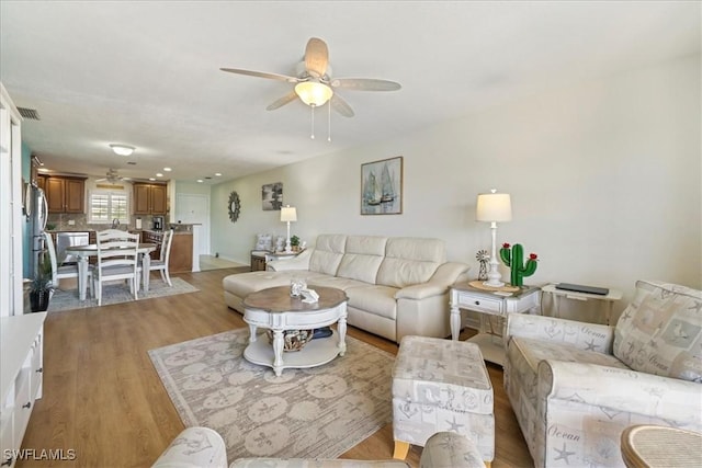 living area with visible vents, light wood-type flooring, and ceiling fan