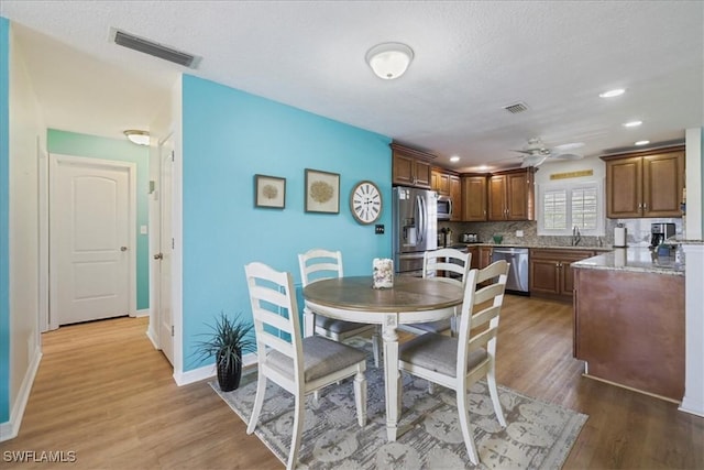 dining area with wood finished floors, ceiling fan, and visible vents