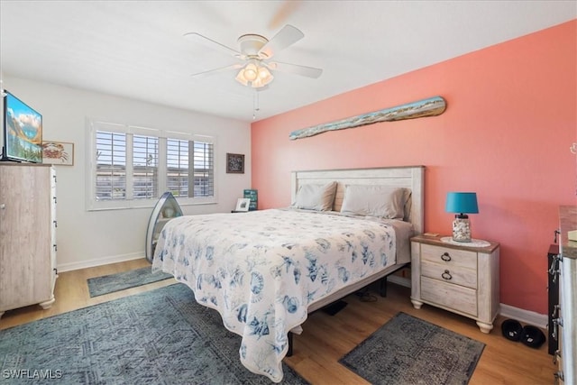 bedroom featuring baseboards, a ceiling fan, and wood finished floors