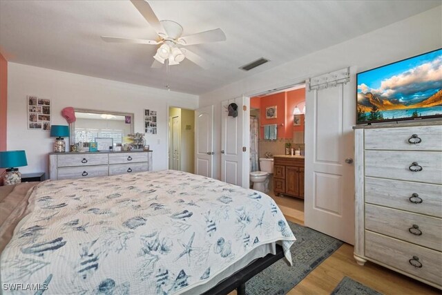 bedroom featuring visible vents, ceiling fan, light wood finished floors, and ensuite bath