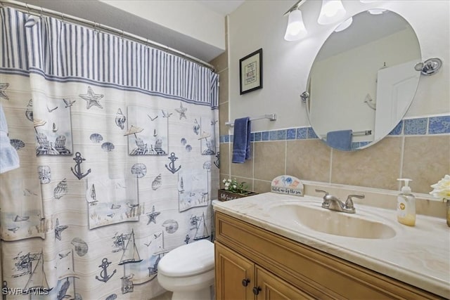 bathroom featuring toilet, curtained shower, vanity, and tile walls