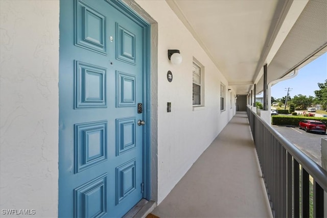 doorway to property featuring covered porch and stucco siding