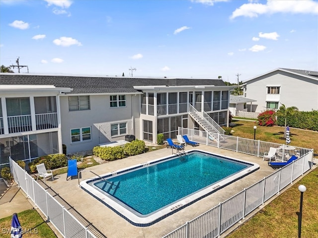 community pool with fence, a patio area, and a sunroom