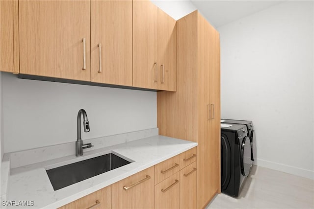 clothes washing area with independent washer and dryer, cabinet space, and baseboards