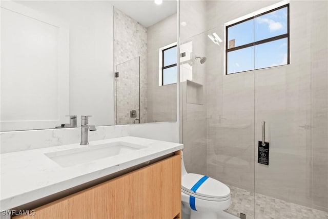 bathroom featuring toilet, vanity, and a stall shower