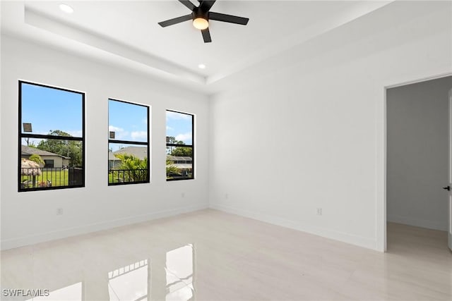 spare room with healthy amount of natural light, recessed lighting, a tray ceiling, ceiling fan, and baseboards