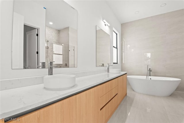 full bathroom featuring double vanity, tile patterned floors, a shower stall, and a soaking tub